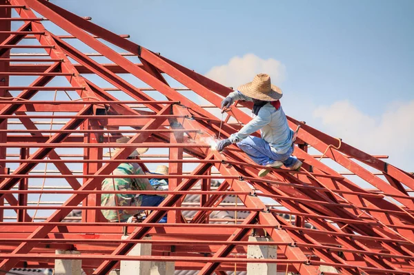 在有云彩和天空的建筑工地安装房屋屋顶钢架结构的建筑工人 — 图库照片