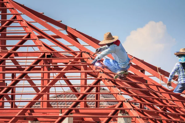 在有云彩和天空的建筑工地安装房屋屋顶钢架结构的建筑工人 — 图库照片