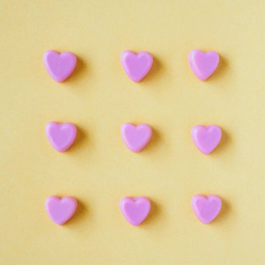 Sevgililer Günü geçmişi, sarı arka planda kalp şeklinde şekerler.