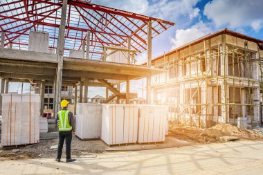 Asyalı işadamı inşaat mühendisi koruyucu miğfer ve bina inşaatında kullanılacak planlar.