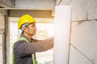 Korumalı miğferli genç mühendis bina inşaatında çalışıyor.