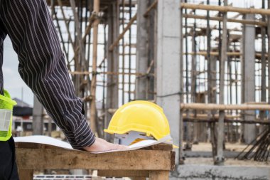 Genç iş adamı profesyonel mühendis bina inşaatında proje üzerinde çalışıyor.