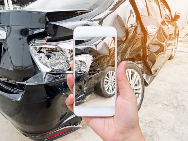 Kadın cep telefonuyla sigorta için araba kazası fotoğrafı çekiyor.