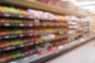 Süpermarketin arka planında taze meyve ve sebze rafları olan bir market.