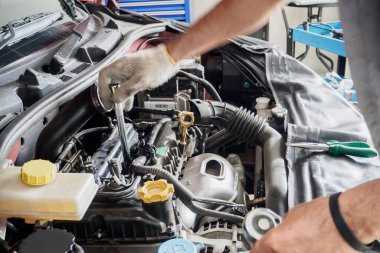 Araba servis merkezinde ingiliz anahtarı çalışan ve araba tamir eden bir tamirci.