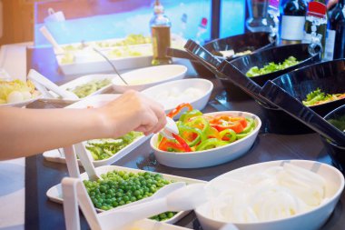 Salata büfesi restoranında sebze malzemesi seçen Asyalı kadın.