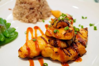 Baharatlı soslu ızgara tavuk bifteği ve pilav.