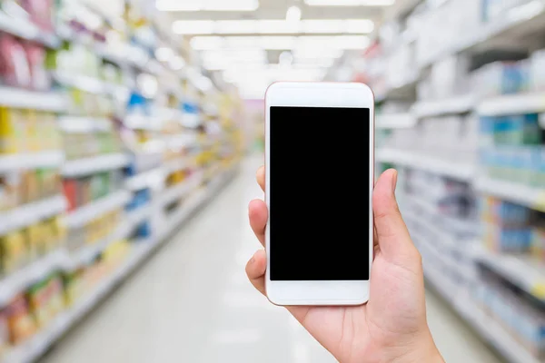 Mão Feminina Segurando Telefone Celular Com Fundo Borrão Supermercado Conceito — Fotografia de Stock