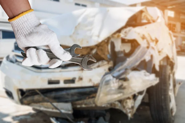 自動車整備士の手は車の衝突事故の損傷の背景とレンチを保持します — ストック写真