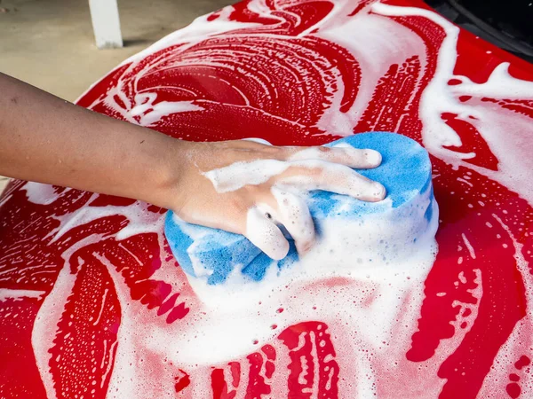 Erkek eli, arabayı yıkamak için mavi sünger.