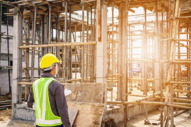 Asyalı işadamı inşaat mühendisi koruyucu miğfer ve bina inşaatında kullanılacak planlar.