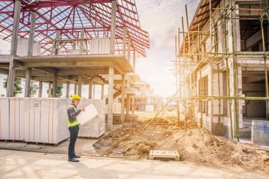 Asyalı işadamı inşaat mühendisi koruyucu miğfer ve bina inşaatında kullanılacak planlar.