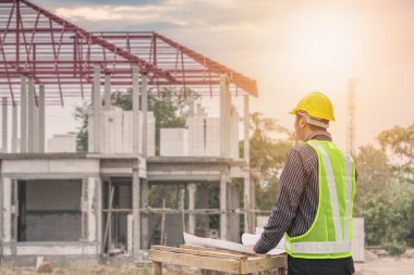 Asyalı işadamı inşaat mühendisi koruyucu miğfer ve bina inşaatında kullanılacak planlar.