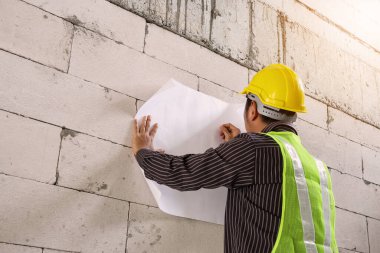 Korumalı miğferli genç mühendis bina inşaatında çalışıyor.