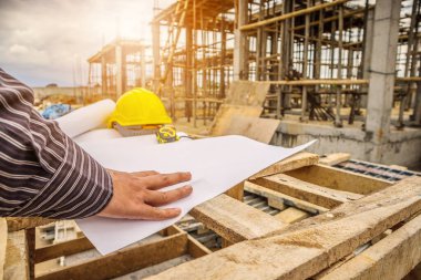 Genç iş adamı profesyonel mühendis bina inşaatında proje üzerinde çalışıyor.