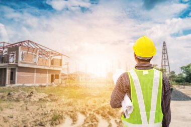 Asyalı işadamı inşaat mühendisi koruyucu miğfer ve bina inşaatında kullanılacak planlar.