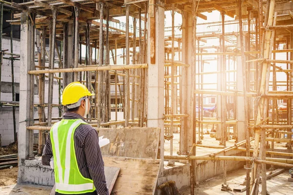 Asyalı işadamı inşaat mühendisi koruyucu miğfer ve bina inşaatında kullanılacak planlar.