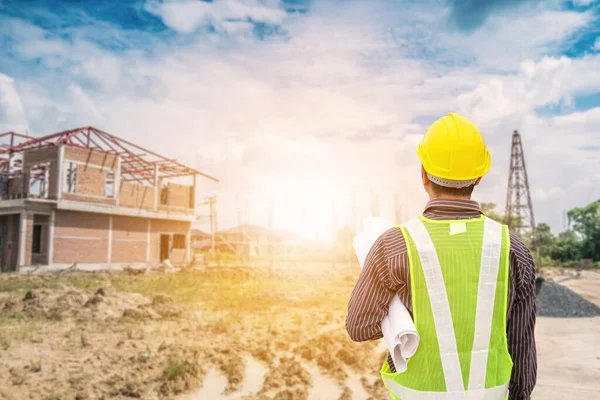 Asyalı işadamı inşaat mühendisi koruyucu miğfer ve bina inşaatında kullanılacak planlar.