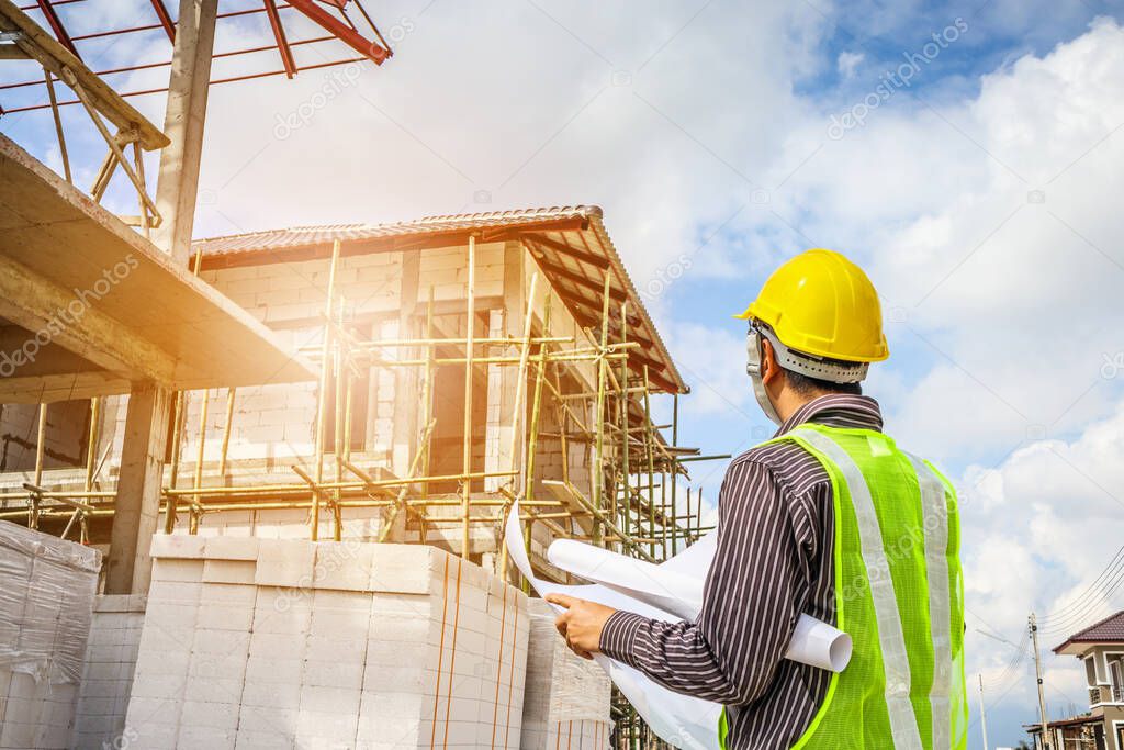 Asian business man construction engineer worker in protective helmet and blueprints paper on hand at house building site