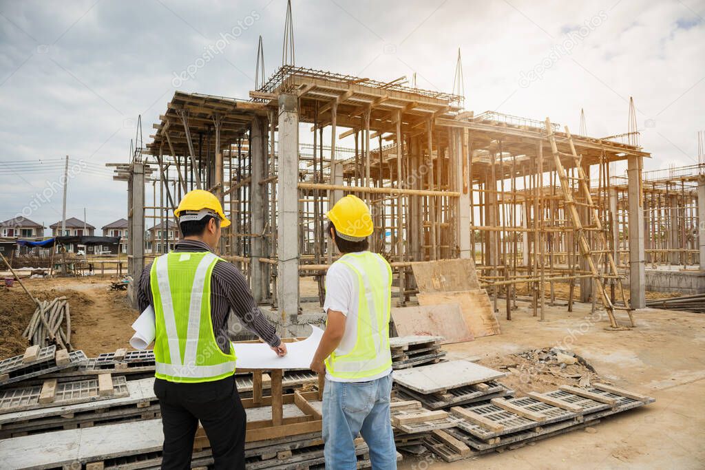 Asian business man construction manager and engineer worker in protective helmet hold blueprints paper on hand at house building site