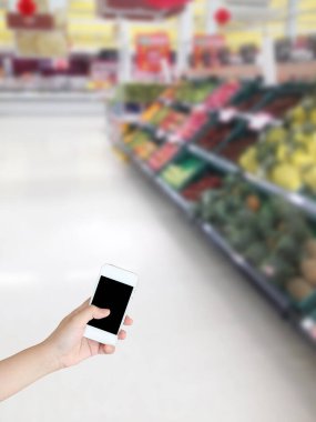 Sebzeli cep telefonu ve markette rafta duran meyve bulanık arka plan.