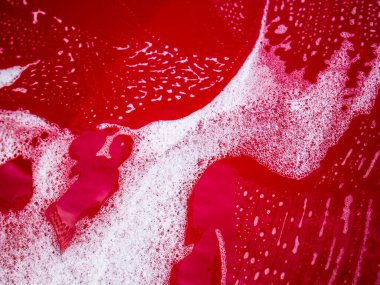 Kırmızı arabanın üzerinde sabunla araba yıkama.