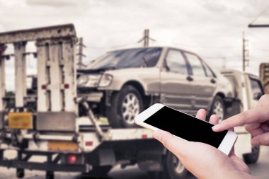 El, trafik kazasından sonra çekçekilen aracın yanında acil yol servisi için cep telefonu kullanıyor.