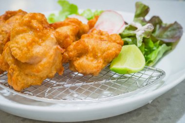 Japon usulü kızarmış tavuk, sebzeli ve limonlu beyaz tabak.