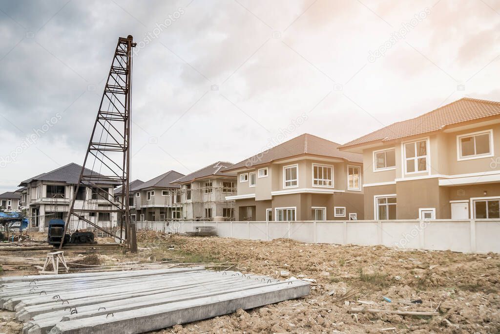 house building at construction site with pile driver and precast concrete piles