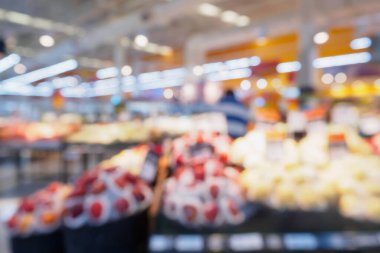 Süpermarketin arka planında taze meyve ve sebze rafları olan bir market.