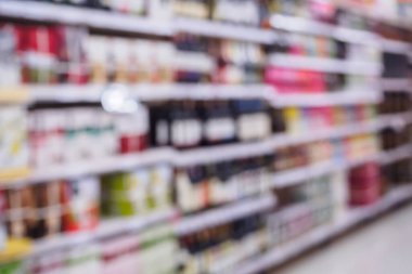 Şarap şişeleri ve içki rafları süpermarkette ya da likör dükkanında bulanık arka plan