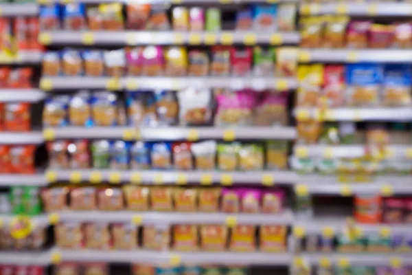 Abstract blur supermarket with variety of fast food snacks chips product on the shelves in store defocused background