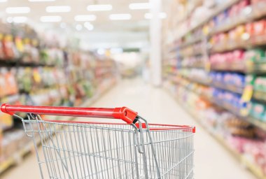 Soyut bulanık süpermarket indirim mağazası koridoru ve ürün rafları olan boş alışveriş arabası.