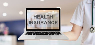 Kadın doktor, sağlık sigortası metniyle dizüstü bilgisayarı gösteren bulanık hastane odası sağlık hizmeti kavramına sahip.