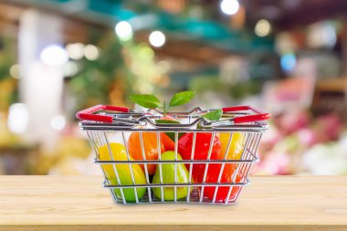 Marketin arka planında, ahşap masada meyveli alışveriş sepeti.