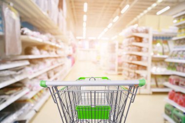 Süpermarket koridoru ürün rafları içi bulanık arka plan ve boş alışveriş arabası 