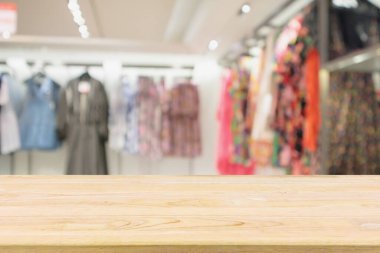 Boş ahşap masa ve alışveriş merkezindeki şık butik giyim mağazası vitrinleri.