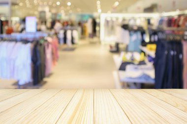 Boş ahşap masa ve alışveriş merkezindeki şık butik giyim mağazası vitrinleri.