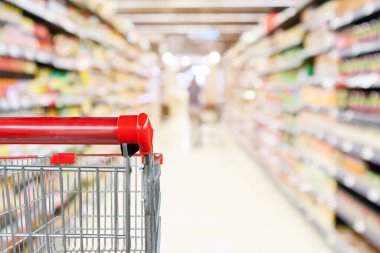 Soyut bulanık süpermarket indirim mağazası koridoru ve ürün rafları olan boş alışveriş arabası.