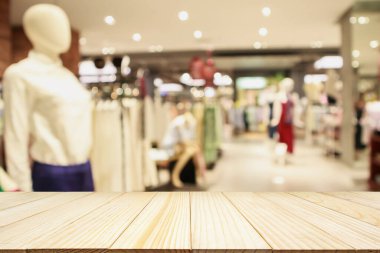 Boş ahşap masa ve alışveriş merkezindeki şık butik giyim mağazası vitrinleri.