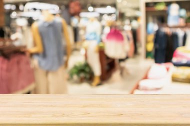 Boş ahşap masa ve alışveriş merkezindeki şık butik giyim mağazası vitrinleri.