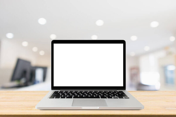 Laptop with blank screen on desk table with blur office interior background