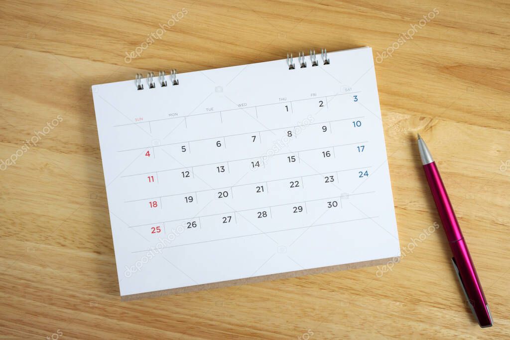 Calendar page with pen on wooden desk table