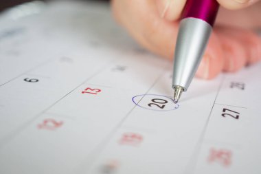 takvim sayfasında kalem çember işareti tutan kadın eli