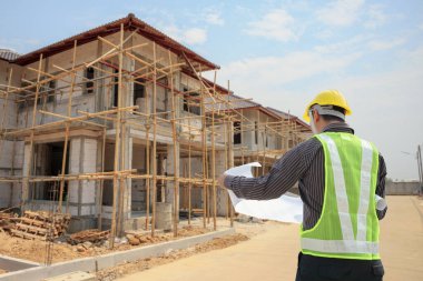 İnşaat alanının arka planında koruyucu mimar ve bina planları olan profesyonel mühendis.