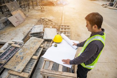 Genç iş adamı profesyonel mühendis bina inşaatında proje üzerinde çalışıyor.