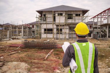 Asyalı işadamı inşaat mühendisi koruyucu miğfer ve bina inşaatında kullanılacak planlar.