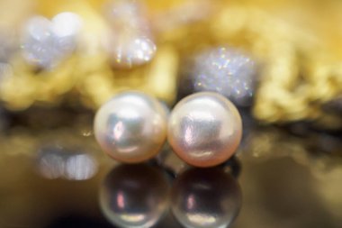 Altın sarısı arka planda yansıması olan inci küpeler.