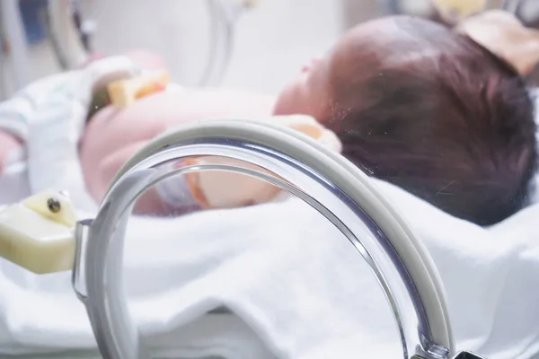 Newborn baby girl inside incubator in hospital post delivery room