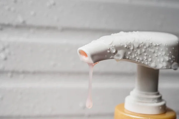 Water drop on liquid soap dispenser pump during bath time